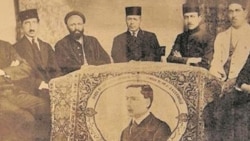 جمعی از مشروطه‌خواهان کنار فرشی که با عکس باسکرویل بافته شده است