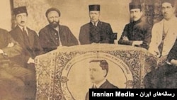 جمعی از مشروطه‌خواهان کنار فرشی که با عکس باسکرویل بافته شده است