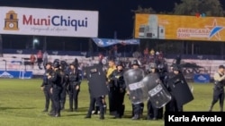 ARCHIVO - Un grupo antimotines custodia al equipo de árbitros que intenta salir del estadio Las Victorias, en Chiquimula, Guatemala, mientras asistentes al partido entre el Sacachispas y el Suchitepéquez los espera para abuchearlos, el 16 de noviembre de 2024.