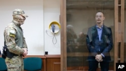 FILE -Ivan Safronov, an adviser to the director of Russia's state space corporation, stands in a cage in a courtroom in Moscow, July 16, 2020. Safronov, who rose to prominence as a journalist, was arrested this month on treason charges.