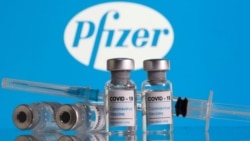 FILE - Vials labelled 'COVID-19 Coronavirus Vaccine' and a syringe are seen in front of the Pfizer logo in this illustration taken Feb. 9, 2021.