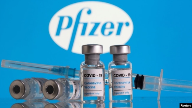 FILE - Vials labelled 'COVID-19 Coronavirus Vaccine' and a syringe are seen in front of the Pfizer logo in this illustration taken Feb. 9, 2021.