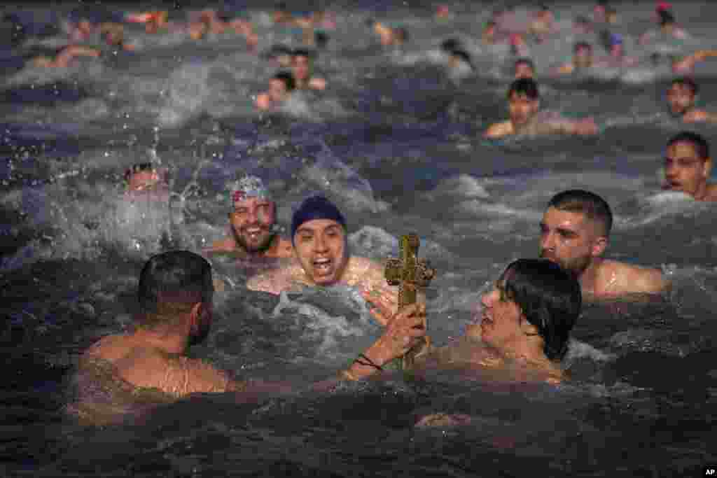 Greek Orthodox faithful hold up a wooden crucifix after being retrieved in the Golden Horn during the Epiphany ceremony in Istanbul, Turkey.