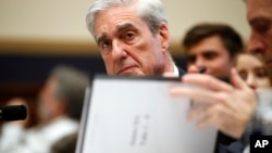 Former special counsel Robert Mueller checks pages in the report as he testifies before the House Judiciary Committee on his report on Russian election interference, Capitol Hill, July 24, 2019 in Washington.