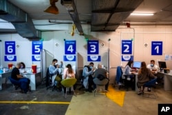 FILE - Israelis receive a Pfizer-BioNTech COVID-19 vaccine from medical professionals at a coronavirus vaccination center set up on a shopping mall parking lot in Givataim, Israel, Feb. 4, 2021.