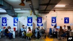 FILE - Israelis receive a Pfizer-BioNTech COVID-19 vaccine from medical professionals at a coronavirus vaccination center set up on a shopping mall parking lot in Givataim, Israel, Feb. 4, 2021.