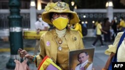 A royalist supporter holds a portrait of the late king Bhumibol Adulyadej while waiting for the motorcade of Thailand&#39;s King Maha Vajiralongkorn to pass in Bangkok.