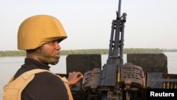 Un officier de la marine patrouille avec une mitrailleuse sur un bateau au large de la côte atlantique dans l'Etat de Bayelsa du Nigeria, 19 décembre 2013. 