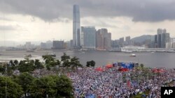 Manifestantes pro China sostienen banderas chinas y carteles que leen "Apoyamos a la policía" durante una manifestación afuera de la legislatura en Hong Kong, el domingo 30 de junio del 2019. (AP Foto/Kin Cheung)