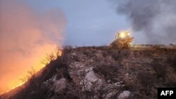 This handout picture courtesy of the Texas A&M Forest Service and taken on Feb. 27, 2024, shows a Texas A&M Forest Service bulldozer building a containment line as it battles the Windy Deuce Fire in Moore County, Texas.