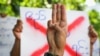缅甸仰光，一名反政变示威者在罢工游行中展示抵抗的三指礼，并打着标语表示对军事政变的不满。（
2021年4月9日） 