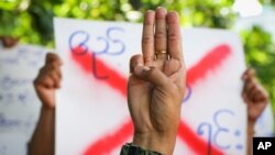 An anti-coup protester shows the three-fingered salute of resistance during a strike walk with slogans to protest the military coup, in Yangon, Myanmar, April 9, 2021. 