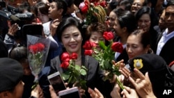 FILE PHOTO - Thailand's former Prime Minister Yingluck Shinawatra, center, receives flowers from her supporters at the Supreme Court after making her final statements in a trial on a charge of criminal negligence in Bangkok, Thailand, Tuesday, Aug. 1, 2017. 