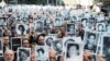 La gente sostiene fotografías de las víctimas mientras suenan las sirenas durante una ceremonia que marca el 30 aniversario del atentado contra el centro judío AMIA que mató a 85 personas en Buenos Aires, Argentina, el jueves 18 de julio de 2024. 