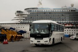 A bus leaves a port where the quarantined Diamond Princess cruise ship is docked, Feb. 15, 2020, in Yokohama, near Tokyo.
