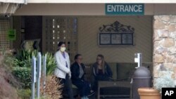 A person wearing a mask walks past a sign banning visitors at the Life Care Center in Kirkland, Wash., near Seattle, Monday, March 2, 2020.