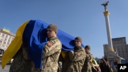 Militares llevan el ataúd del soldado voluntario Bizhan Sharopov, neurobiólogo con doctorado y profesor de la Academia Kyiv-Mohyla, asesinado en una batalla con las tropas rusas cerca de Bakhmut, durante una ceremonia de despedida en la Plaza de la Independencia en Kiev, Ucrania, el lunes 20 de marzo. 2023. (Foto AP/Efrem Lukatsky)