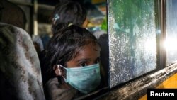 A Rohingya child looks on near a window of a bus during an evacuation after arriving by boat at a port in Krueng Geukuh near Lhokseumawe, North Aceh, Indonesia.