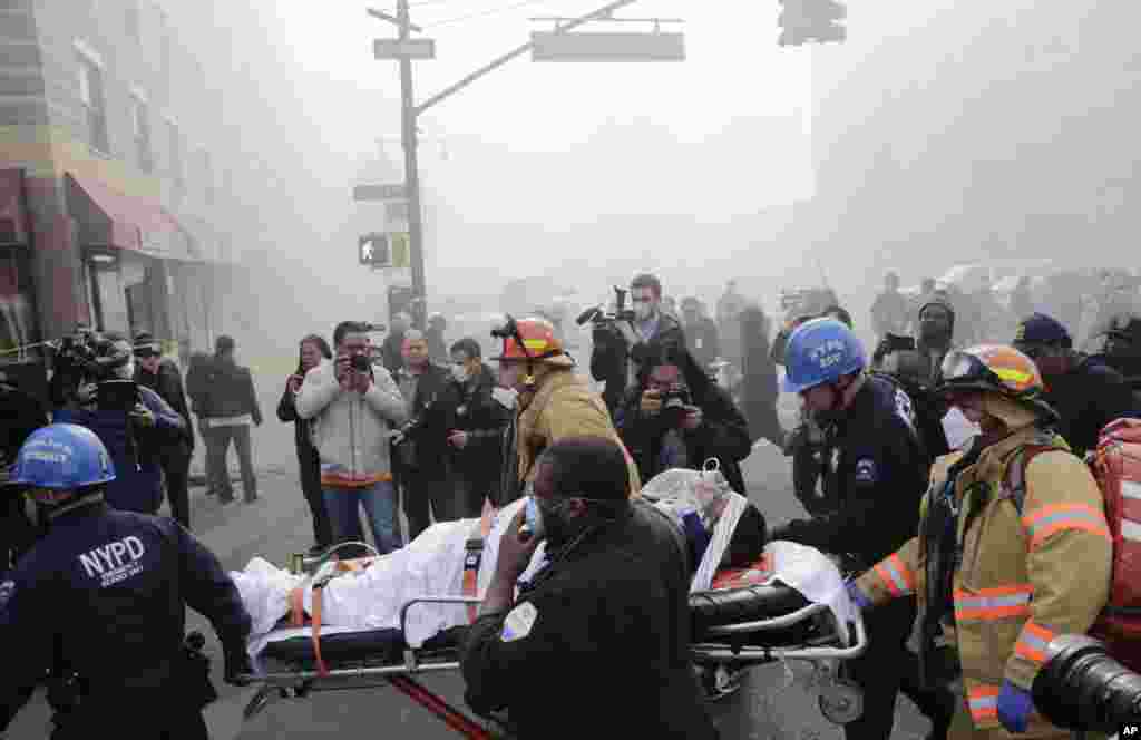 Rescue workers remove an injured person on a stretcher after a building collapse in Harlem, New York, March 12, 2014. 