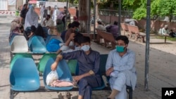 People sit in waiting area of the Benazir Hospital ignore social distancing, during a lockdown to contain the spread of coronavirus, in Rawalpindi, Pakistan, Wednesday, April 22, 2020. (AP Photo/B.K. Bangash)