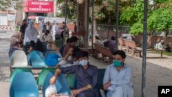 FILE - People sit in waiting area of the Benazir Hospital ignore social distancing, during a lockdown to contain the spread of coronavirus, in Rawalpindi, Pakistan, April 22, 2020. 