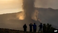 Residents watch from a hill as lava continues to flow from an erupted volcano, on the island of La Palma in the Canaries, Spain, Sept. 24, 2021.