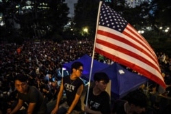 Anti-extradition bill protesters hold an American flag at a gathering at Chater House Garden in Hong Kong, Aug. 16, 2019.