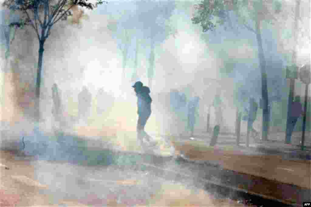 Students walk through a cloud of tear gas, during clashes with riot police in Nanterre, near Paris, Wednesday, Oct. 20, 2010. About 100 students blocked in Nanterre the school entrance and part of highway in front of the school, to protest against raising