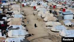 FILE - A woman walks through al-Hol displacement camp in Syria April 2, 2019.