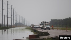 Crews clear debris from Highway 23 during storm Barry in Plaquemines Parish, Louisiana, July 14, 2019. Barry made landfall as a hurricane, but then was downgraded, first to a tropical storm, and then to a tropical depression.