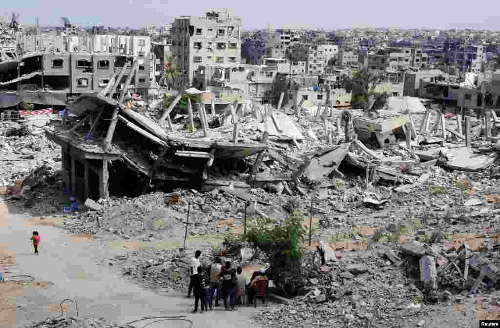 Palestinians sit next to the rubble of houses destroyed in Israel&#39;s military offensive, amid the ongoing conflict between Israel and Hamas, in Khan Younis in the southern Gaza Strip.