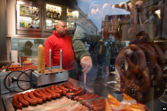 Hot sausages get prepared at a traditional sausage stand (Wuerstelstand), which are named as intangible cultural heritage by the Austrian UNESCO Commission, in Vienna, Austria, Thursday, Nov. 28, 2024. (AP Photo/Heinz-Peter Bader)