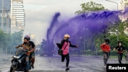 Anti-government protesters escape from a police water cannon with purple dye and tear gas during a protest against the government's handling of the coronavirus disease (COVID-19) pandemic in Din Daeng district of Bangkok, Aug. 29, 2021.