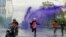 Anti-government protesters escape from a police water cannon with purple dye and tear gas during a protest against the government's handling of the coronavirus disease (COVID-19) pandemic in Din Daeng district of Bangkok, Aug. 29, 2021.