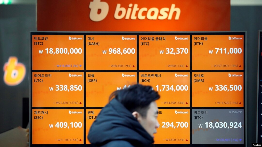 FILE - A man walks past an electric board showing exchange rates of various cryptocurrencies including Bitcoin (top-L) at a cryptocurrencies exchange in Seoul, South Korea, Dec. 13, 2017. (REUTERS/Kim Hong-Ji )