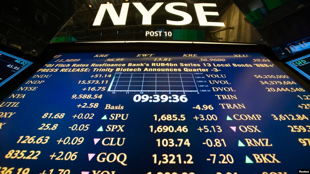 The New York Stock Exchange logo stands above a board displaying stock prices shortly after the beginning of trading, July 30, 2013. 