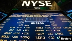 The New York Stock Exchange logo stands above a board displaying stock prices shortly after the beginning of trading, July 30, 2013. 