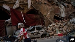 A cyclist rides past destroyed buildings and cars in a neighborhood near the site of last week's explosion that hit the seaport of Beirut, Lebanon, Aug. 11, 2020.