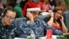 Santa tracker volunteers U.S. Navy Petty Officer Brandon Wright, center, and his wife, Petty Officer Emily Wright, left, take phone calls from children asking where Santa is and when he will deliver presents to their homes, inside a phone-in center during