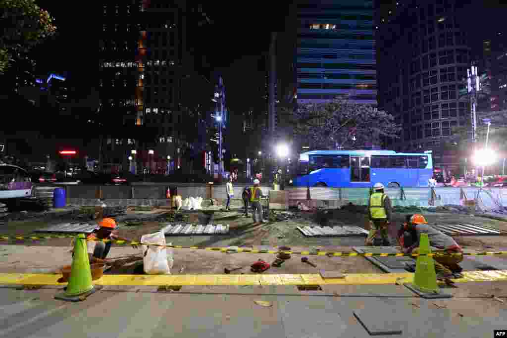 Para pekerja sedang menyelesaikan perbaikan jalan di sekitar Jalan Sudirman di Jakarta menjelang Asian Games ke-18, 12 Juli 2018. (Foto: AFP)