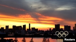 Cincin Olimpiade dengan latar gedung pencakar langit saat matahari terbenam di Tokyo, Jepang, 20 Juli 2021. 