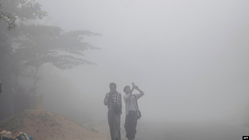 FILE - People walk along a residential street through early morning fog and high levels of air pollution in Yangon on February 14, 2025. (Photo by Sai Aung MAIN / AFP)