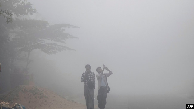 FILE - People walk along a residential street through early morning fog and high levels of air pollution in Yangon on February 14, 2025. (Photo by Sai Aung MAIN / AFP)