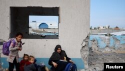 Seorang perempuan dan sejumlah anak-anak tiba di Rafah setelah dievakuasi dari Rumah Sakit Nasser di Khan Younis, Gaza, pada 15 Februari 2024. (Foto: Reuters/Mohammed Salem)