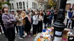 La gente se reúne junto a un monumento improvisado en honor a Matthew Perry afuera del edificio que se muestra en tomas exteriores del programa de televisión "Friends" el lunes 30 de octubre de 2023 en Nueva York.