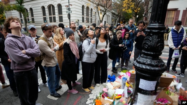 La gente se reúne junto a un monumento improvisado en honor a Matthew Perry afuera del edificio que se muestra en tomas exteriores del programa de televisión "Friends" el lunes 30 de octubre de 2023 en Nueva York.