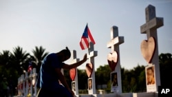 FILE - A man prays at one of the crosses honoring the victims of the Pulse nightclub mass shooting in Orlando, Florida, June 17, 2016.