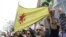 FILE - A man holds a flag of the YPG, a Syria-based Kurdish militant group, during a protest against Turkish President Recep Tayyip Erdogan in front of the Brookings Institution in Washington, where Erdogan was speaking, March 31, 2016.