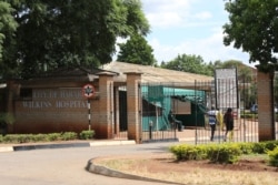 People walk through the entrance gate of Wilkins Hospital in Harare, Zimbabwe’s main COVID-19 inoculation center until vaccine shortages began in May of 2021. (Columbus Mavhunga/VOA)