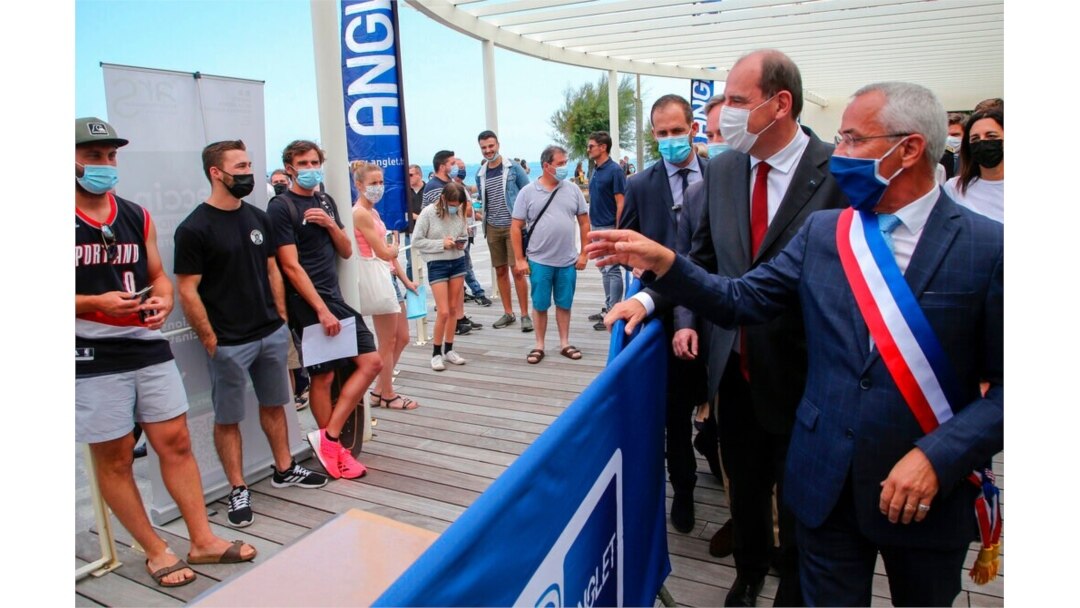 French Prime Minister Jean Castex, second right, and the mayor of Anglet, Claude Olive, right, look at people lining up to get vaccine shots in Anglet, southwestern France, July 17, 2021.
